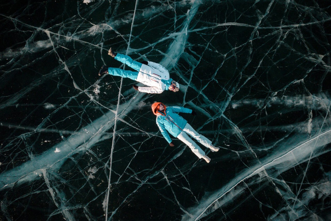Two people laying on the ice of a lake