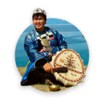 A shaman in traditional clothing performing a ritual with a drum