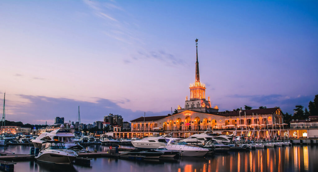 Marine with boats and yachts, marine passenger terminal building of Stalinist architecture with a steeple on the top of a tower in late evening