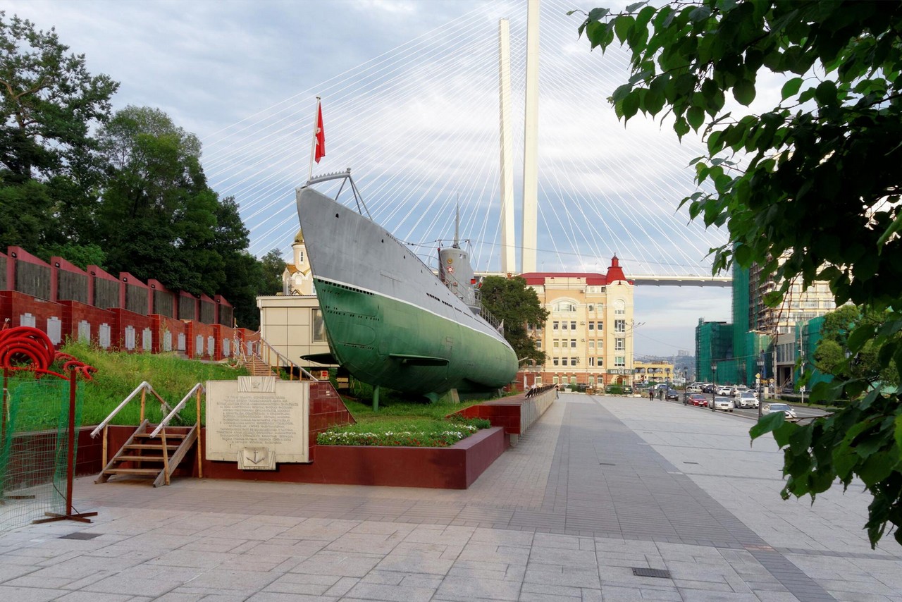 A submarine in front of a bridge and a building