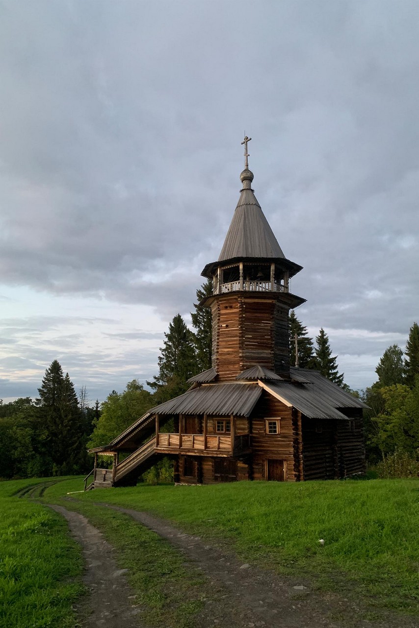 A 30 meters tall tower. It has a square wooden frame resting on a foundation. Above the square frame, there is an octagonal part with the zvonnitsa on top. Then there is a pyramidal (octagonal) roof resting on pillars. The roof is topped with a cross. Wood types are the same as in the churches: pine, spruce and aspen