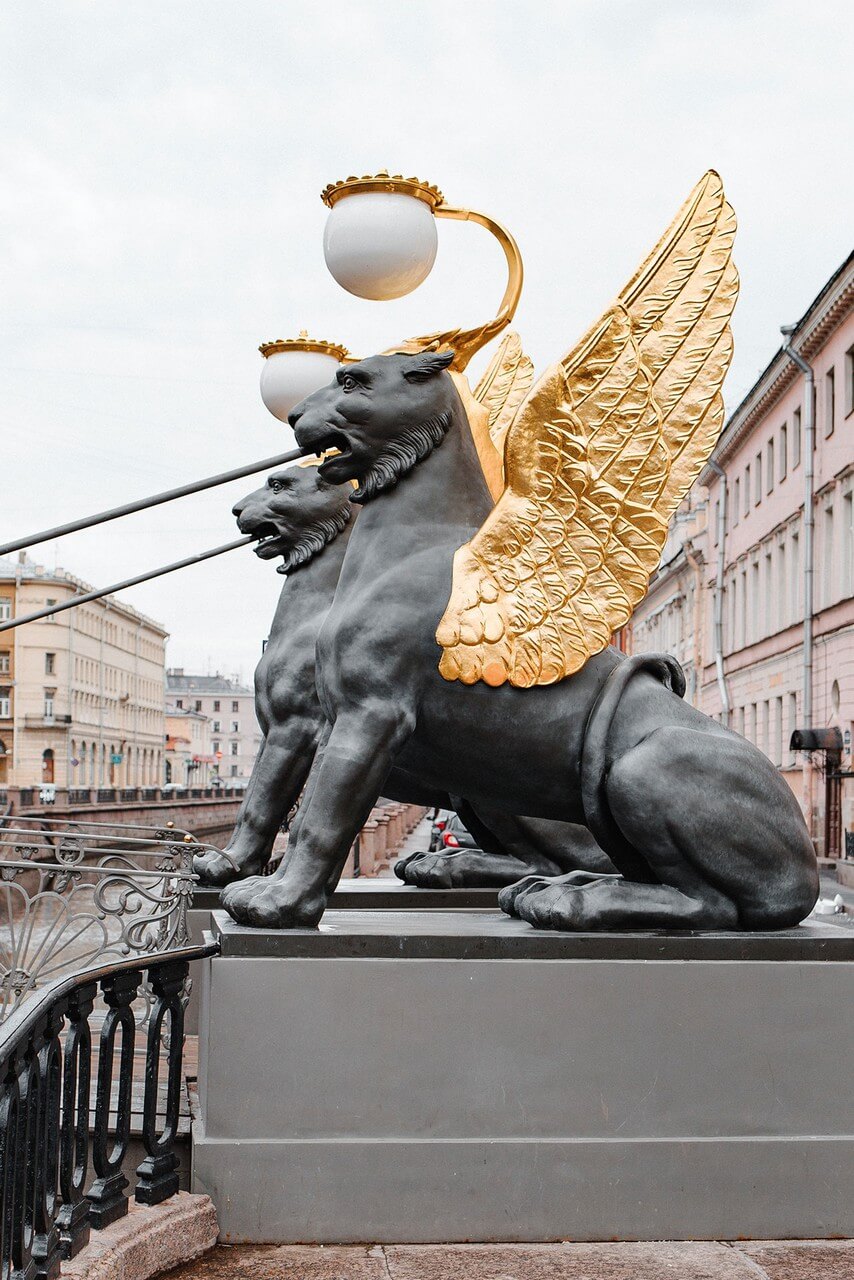 Two griffon statues with gilded wings and lamps over their heads, Lions with eagle wings.