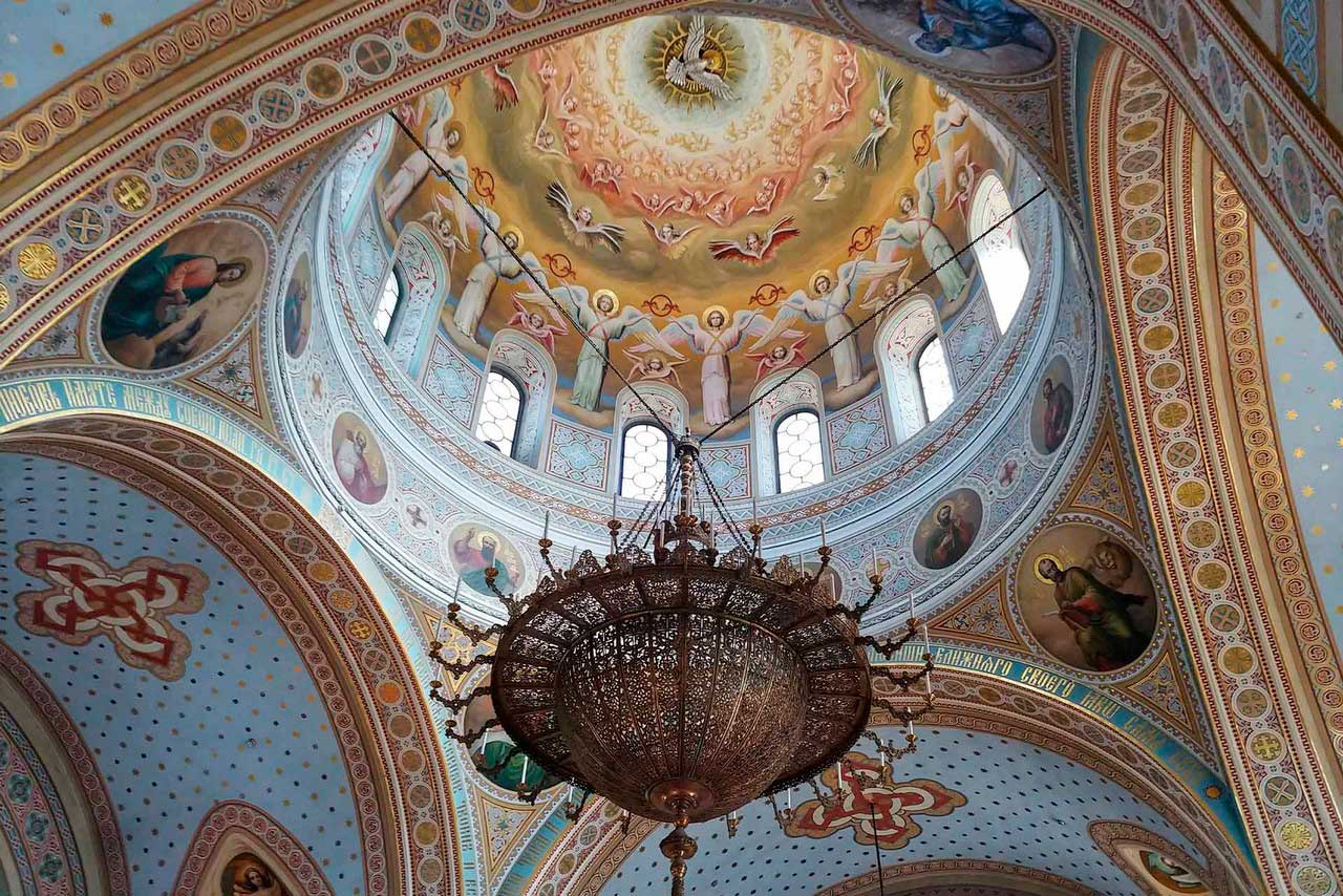 Orthodox cathedral’s dome inside decorated with frescoes and a massive ceiling chandelier