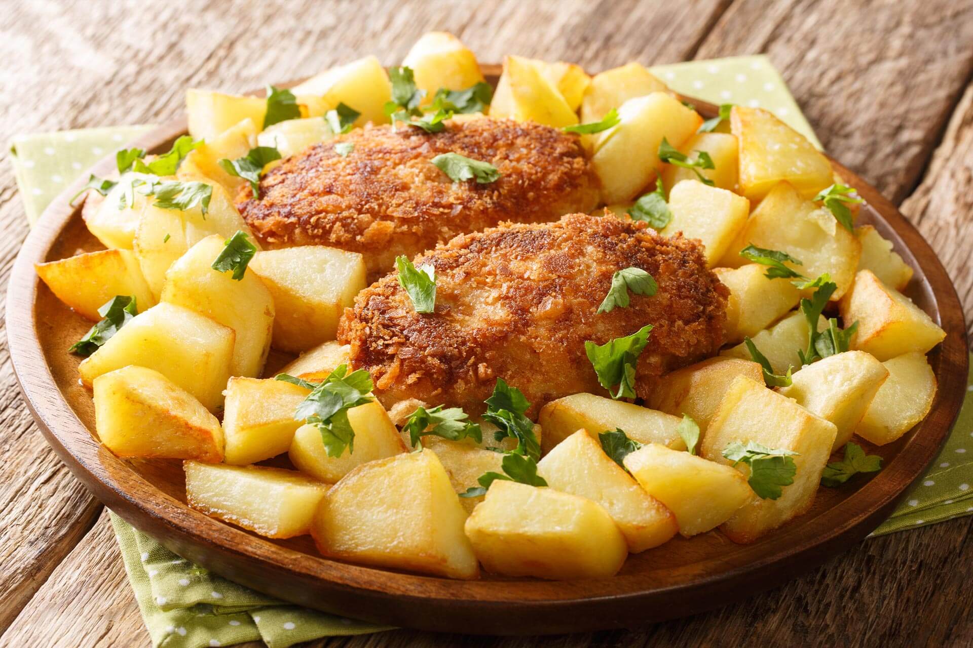 A traditional dish of baked potatoes and two chicken cutlets seasoned with greens