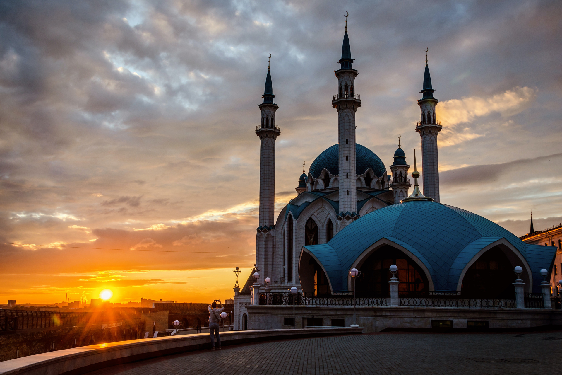 A beautiful modern white mosque with four minarets and blue domes during the sunset