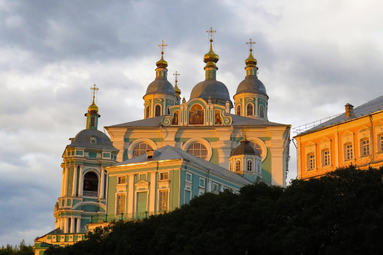 A large beautiful cathedral of turquoise and white colors with silver domes topped with gilded onion-shaped cupola and orthodox crosses during the sunset in a cloudy day