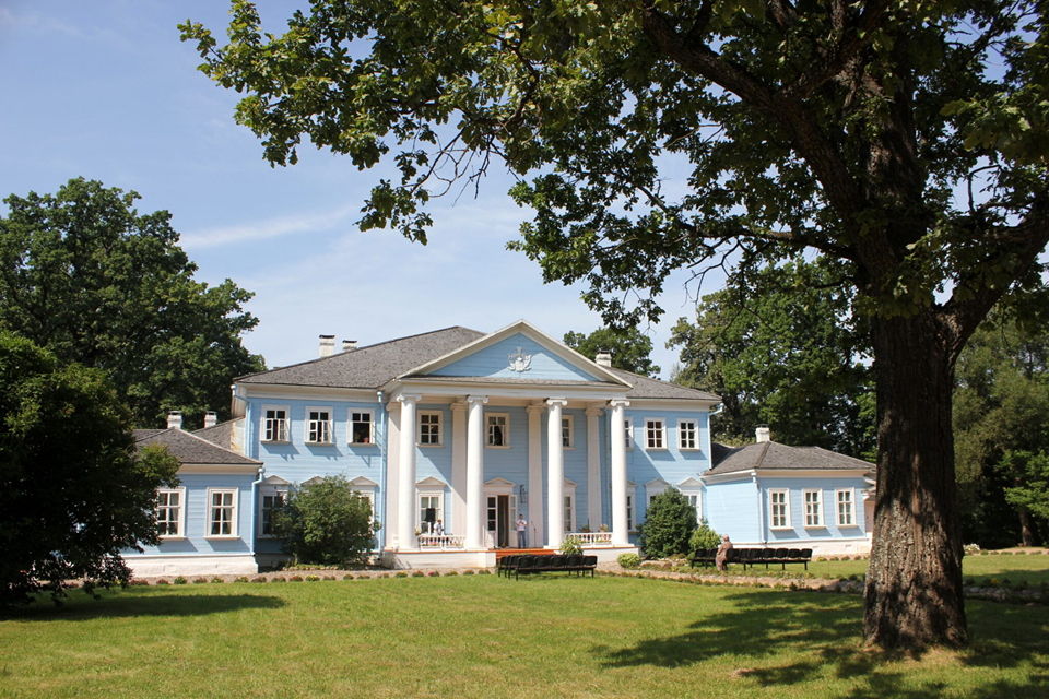 A classic blue and white two-storey mansion with a portico decorated with columns