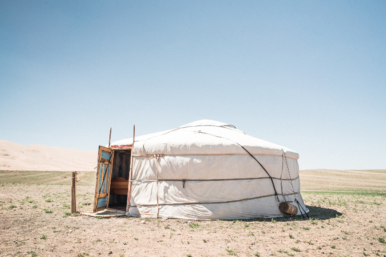 A white nomad tent in a field with an open door