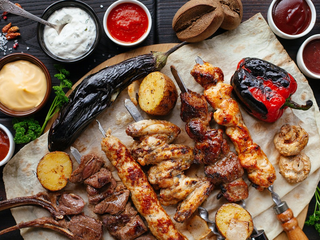 Barbeque of different meat and chicken, grilled vegetables, sauces