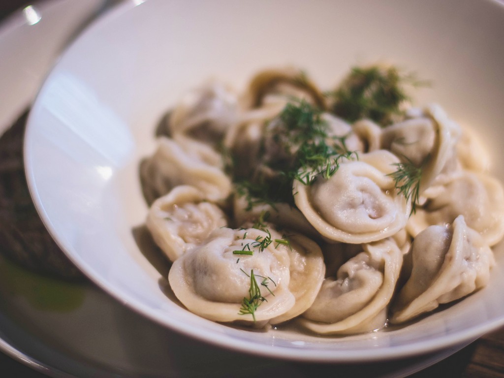 A plate of pelmeni decorated with greens