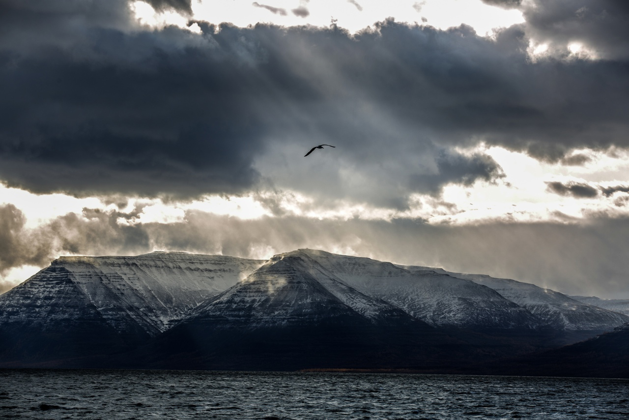 The shoots of sunlight breaking through the clouds over the hills and water