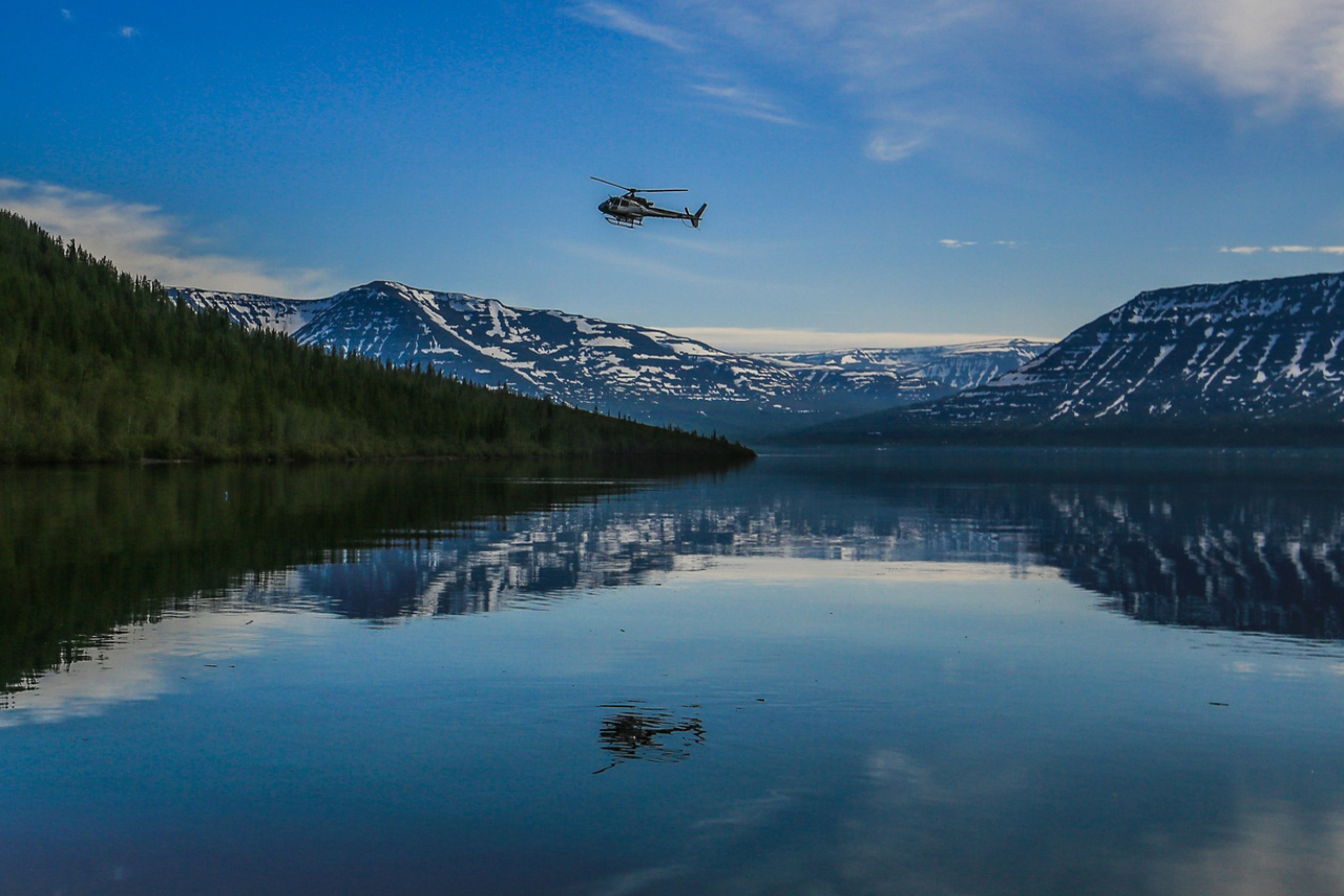 A helicopter over the river surrounded with hills