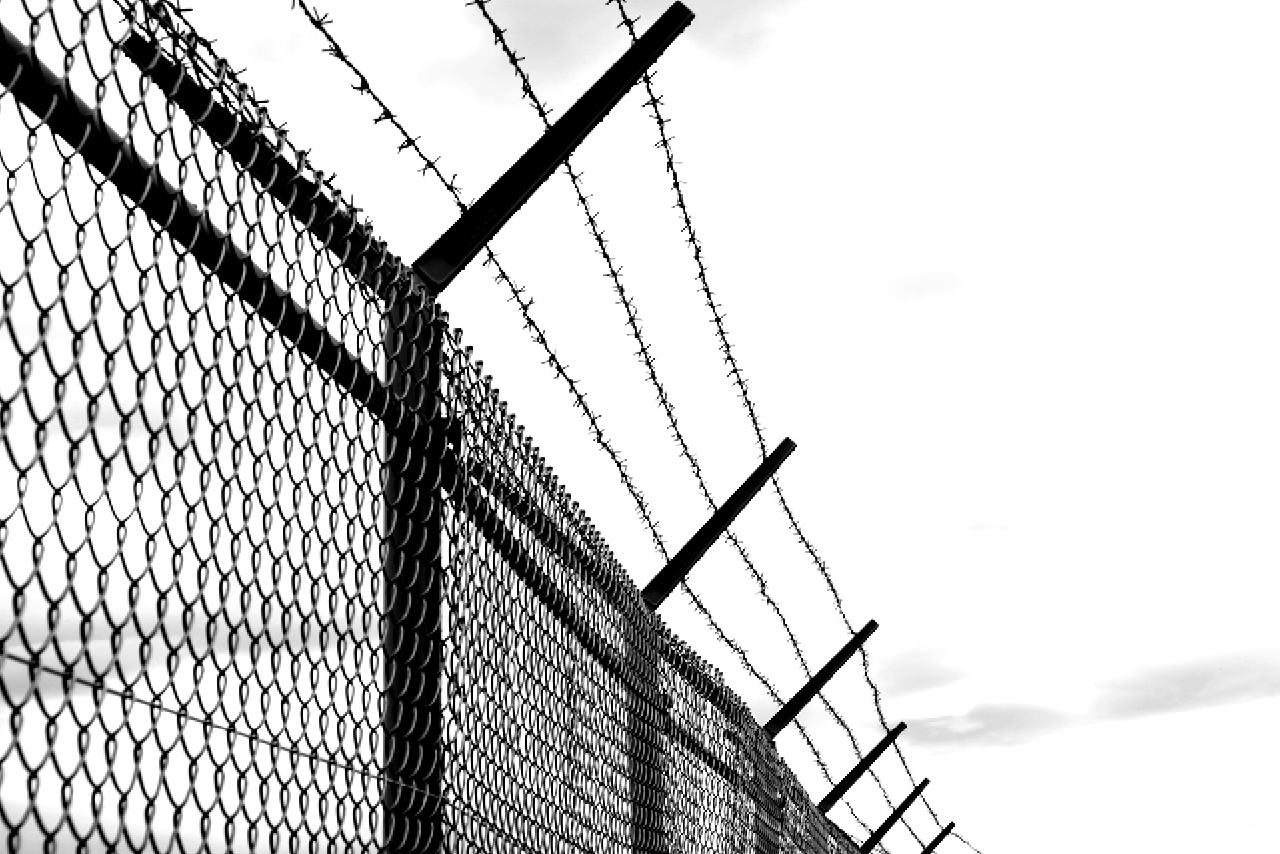 A black and white photo of a barbed wire fence