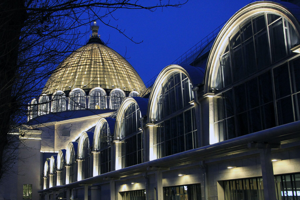 An expo building looking like a palace with in modern style with giant arched windows and glass dome at night