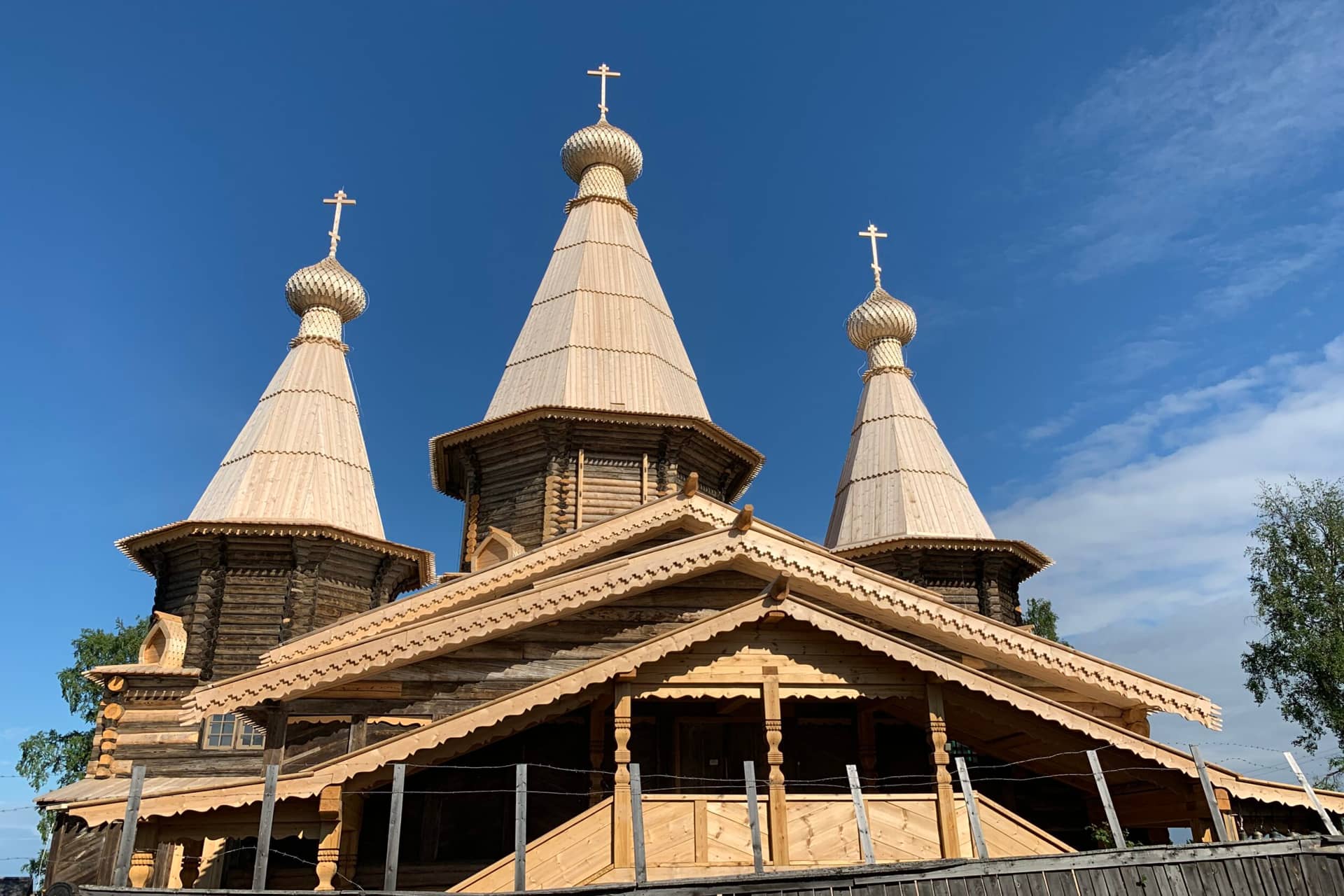 A wooden church with three towers topped with domes and crosses