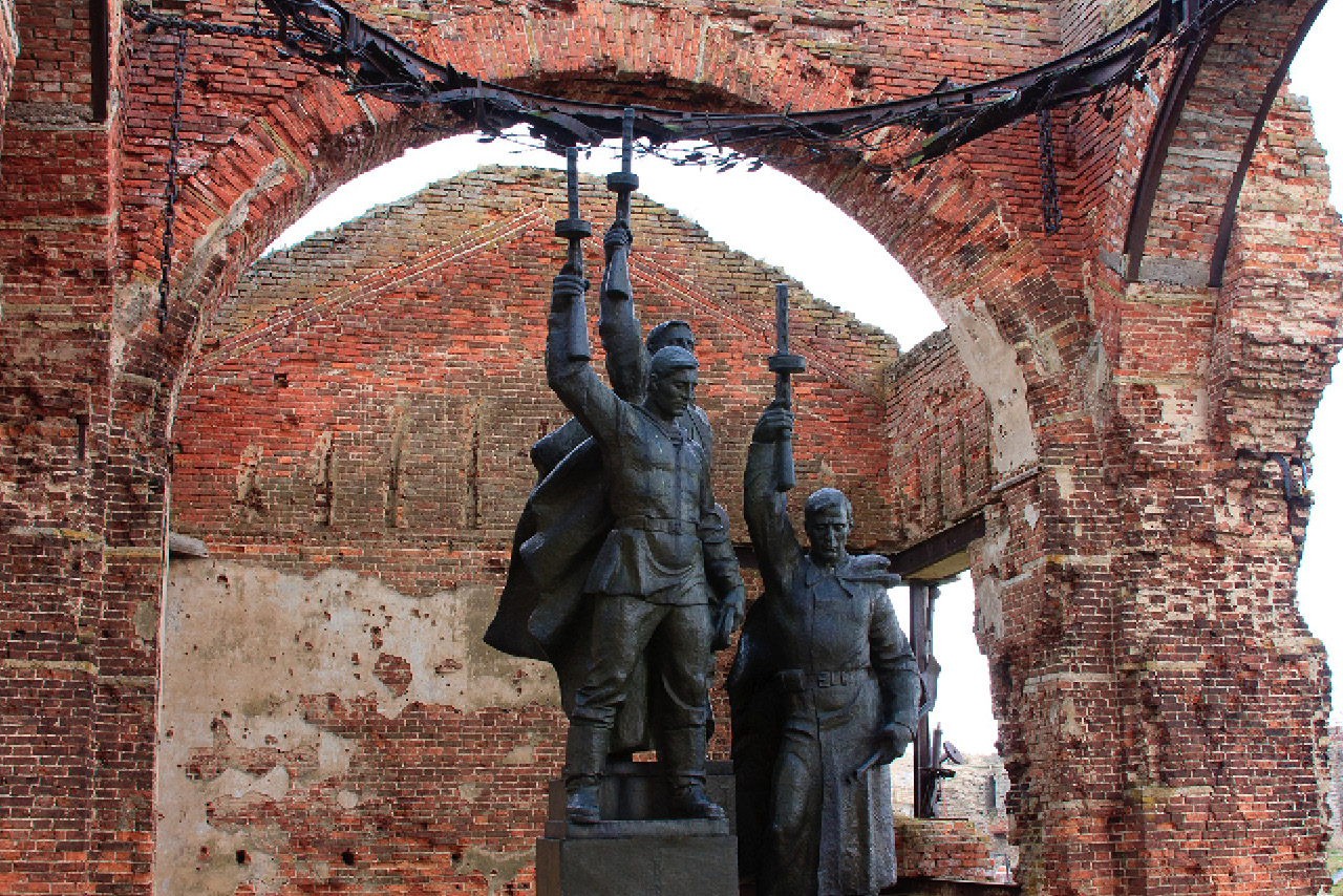 A monument to the soldiers in front of a ruined red brick wall