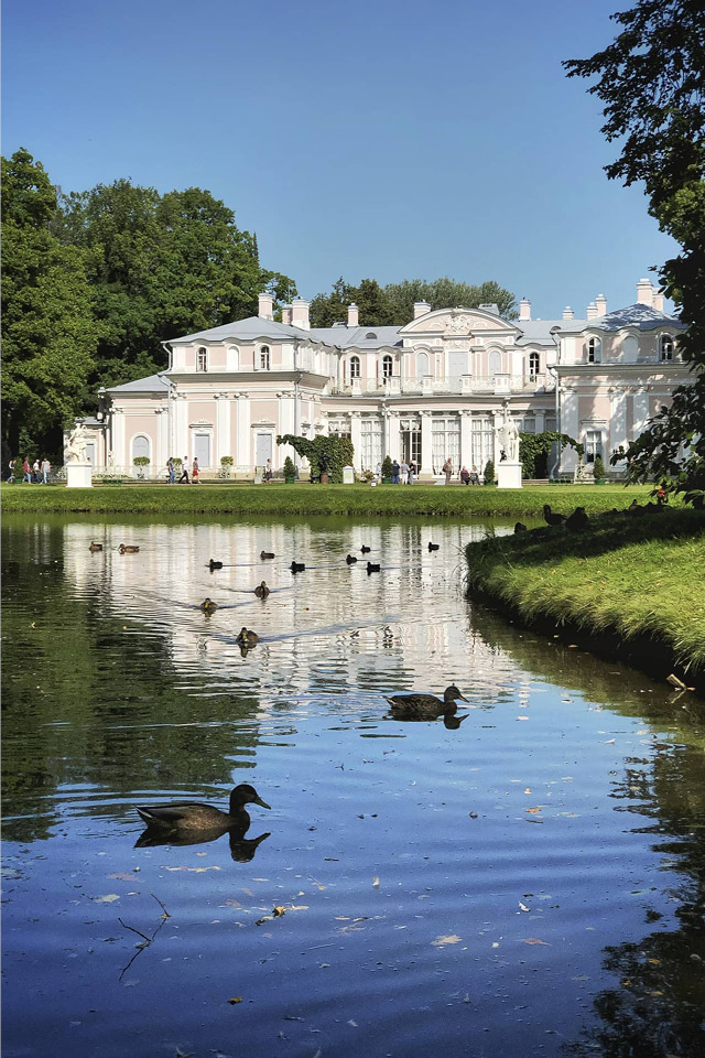 A small palace next to a lake, ducks on the water