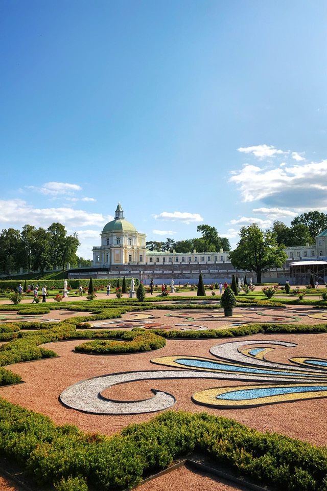 A garden with decorations in the shape of flowers on the floor and a palace in the distance