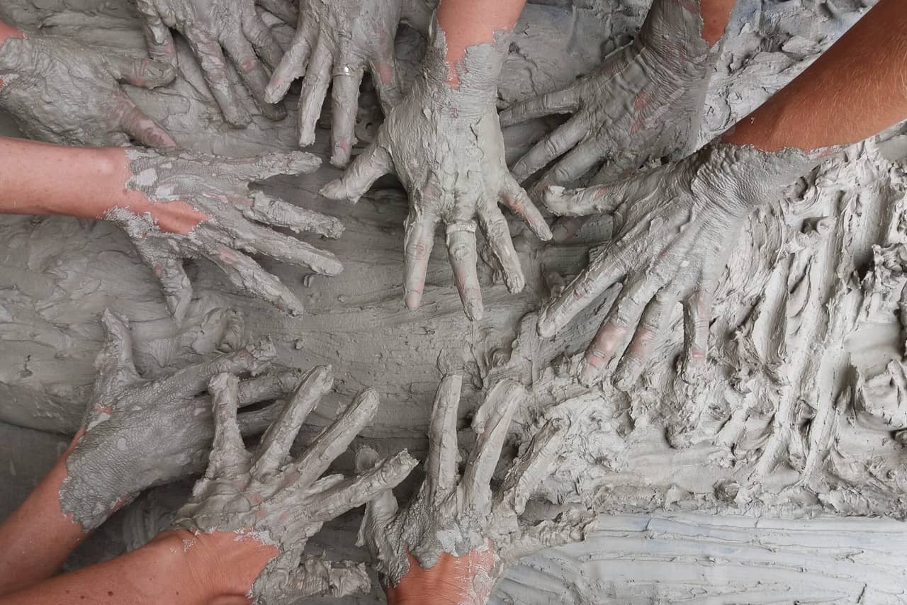 Many hands of people in mud