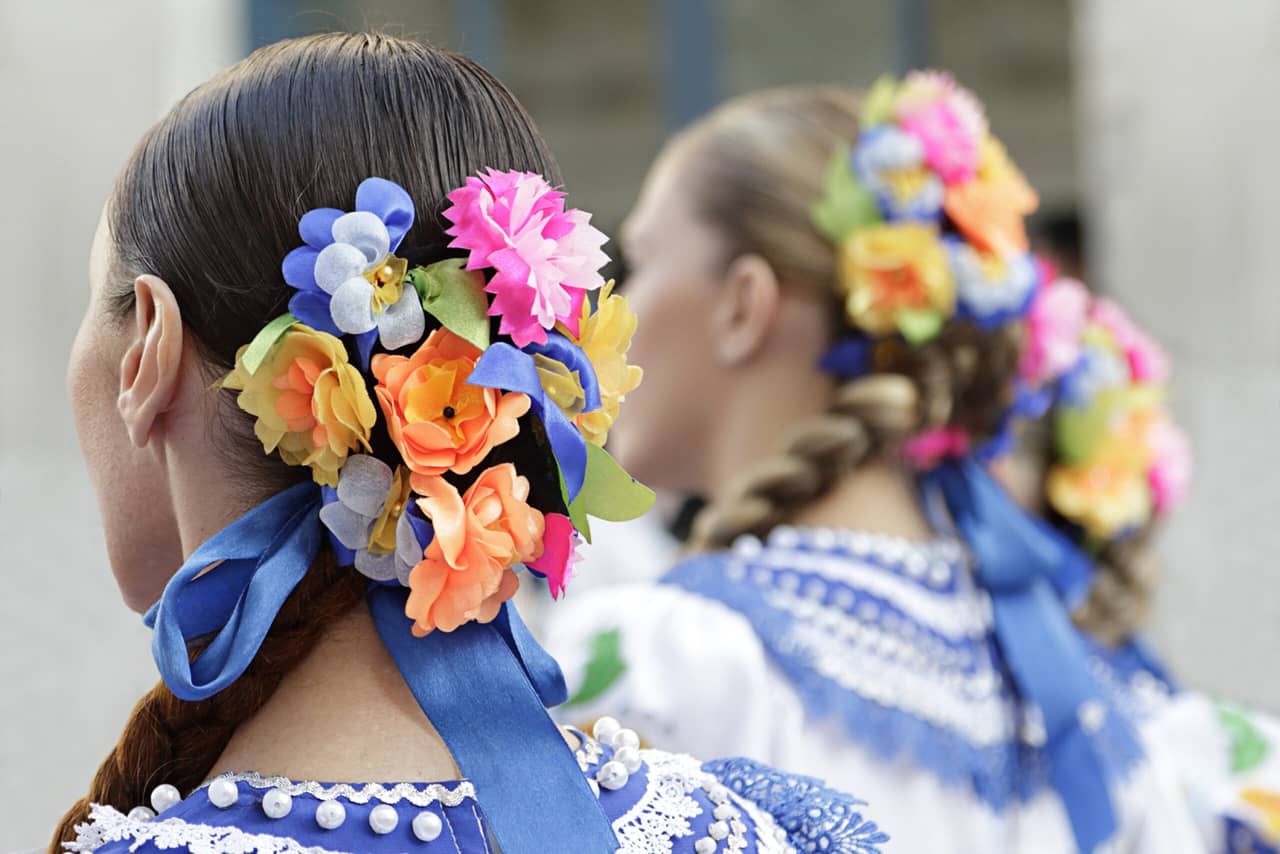 Back of the women wearing traditional dresses and flowers in the hair