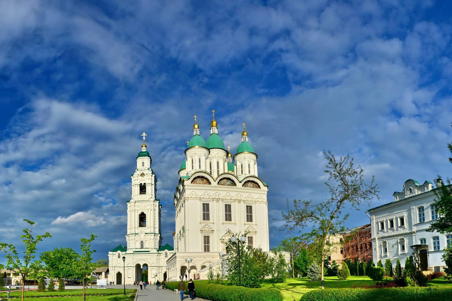 A white cathedral with green domes inside of the Kremlin