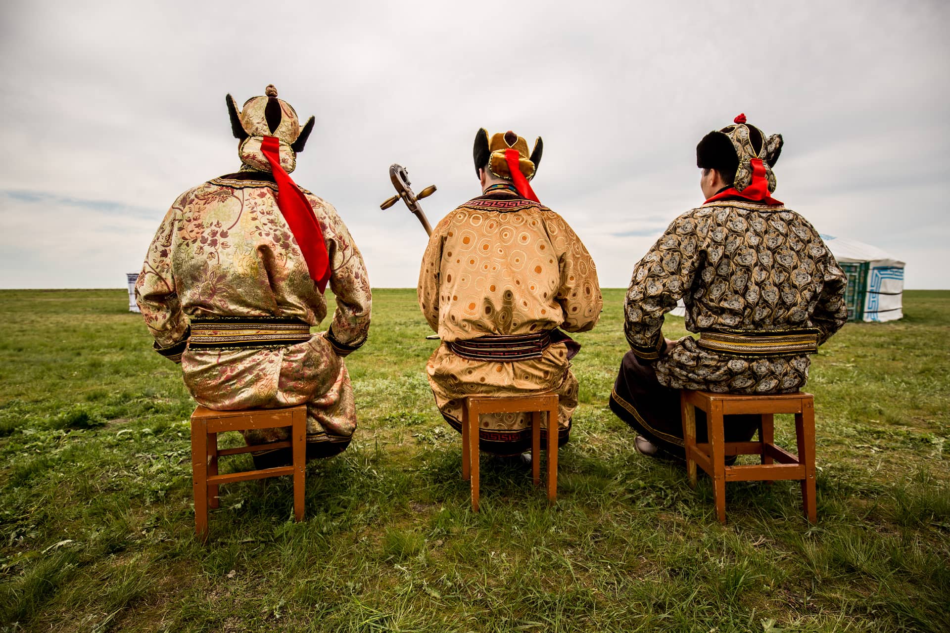 Three Kalmyk men in traditional Kalmyk clothes sitting on chairs