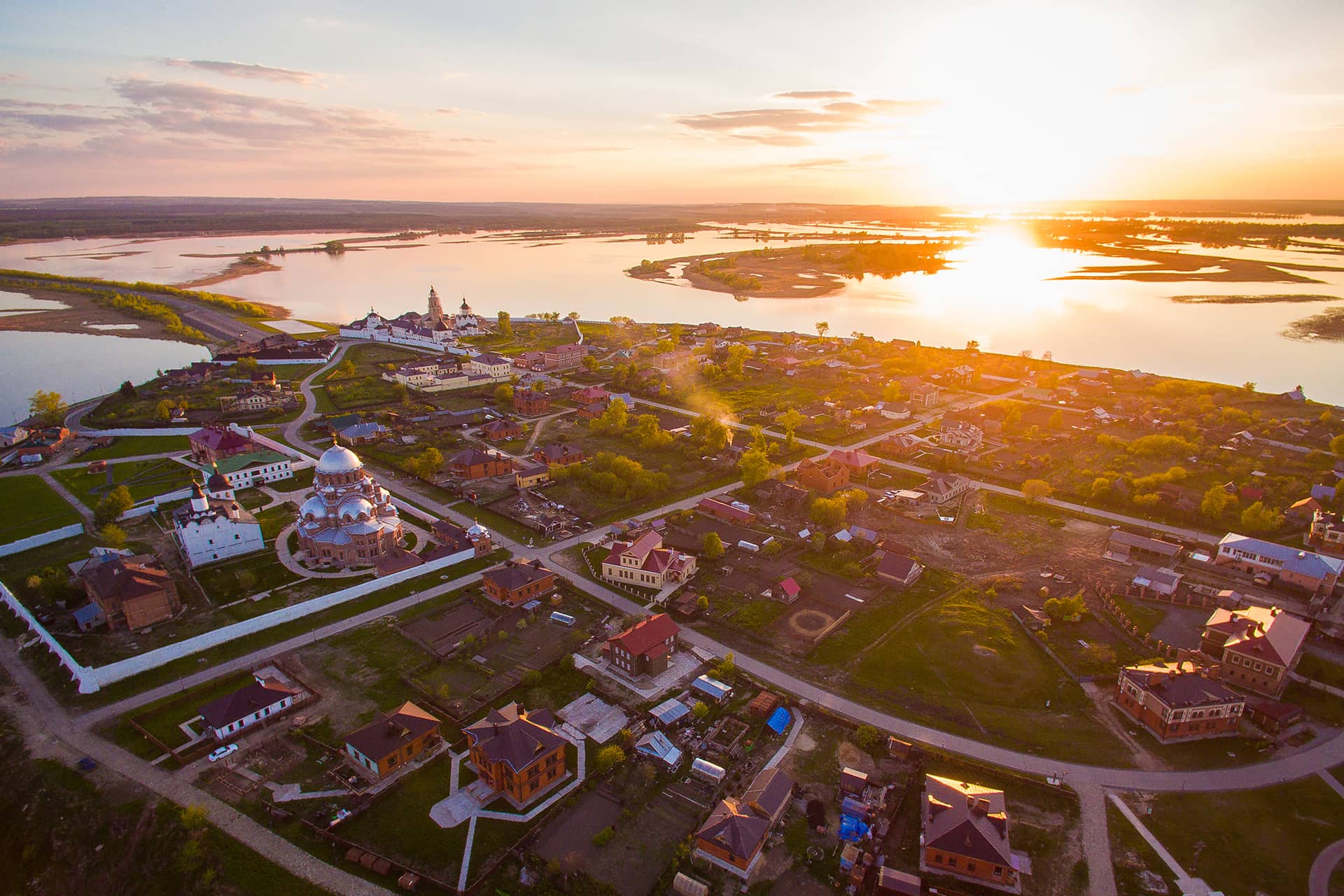 An island town with churches and small houses in Russia, view from the air during the sunset