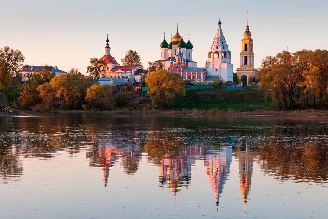 A beautiful ancient Russian city on a bank of a river during the sunrise, monastery consisting of several churches and bell towers