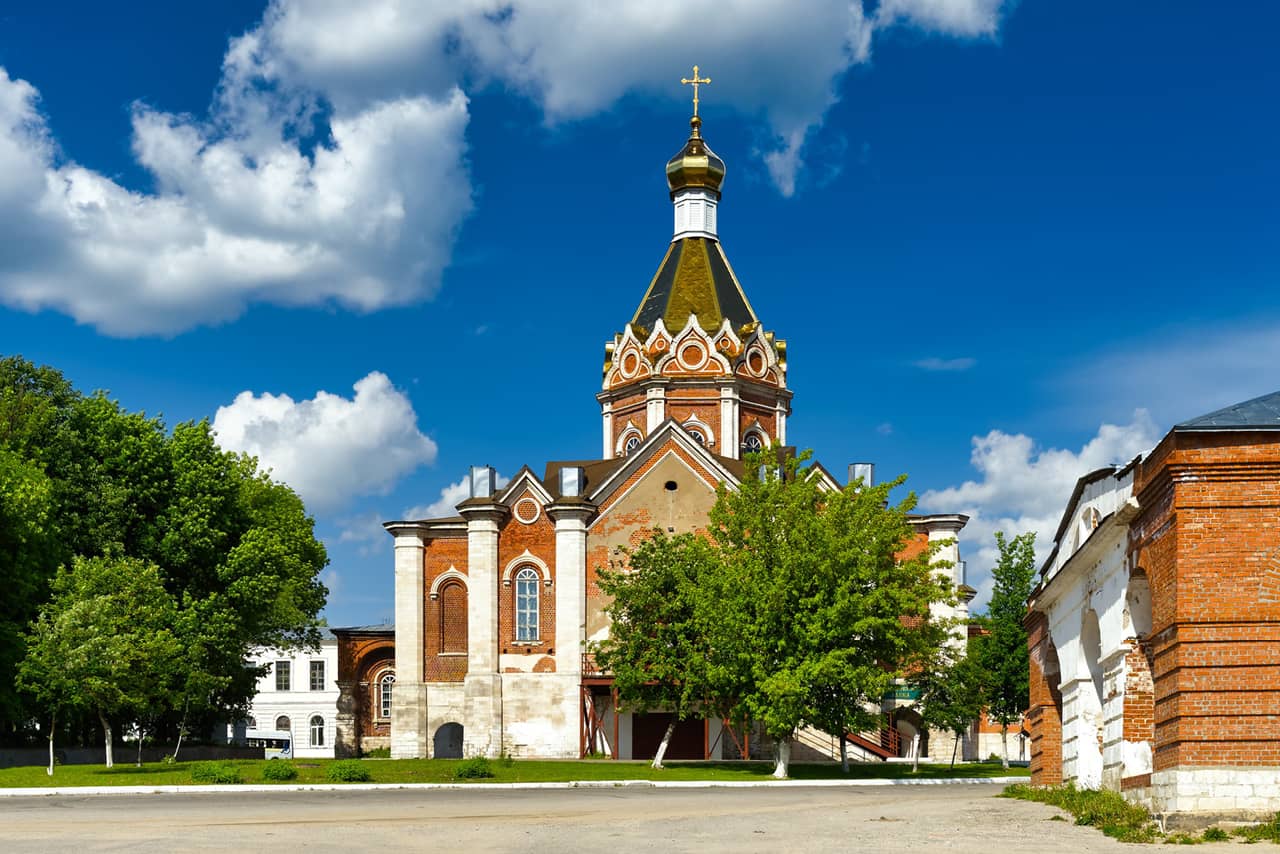 A cathedral in neo-Russian style built of red brick with white decorations, A bell-tower dominating the architectural ensemble of the church