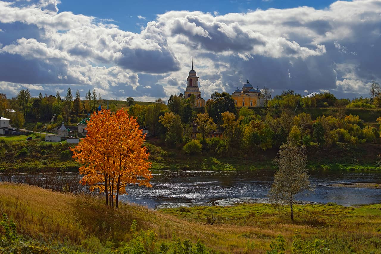 Beautiful autumn nature, an orthodox monastery in the distance behind a river and yellow trees