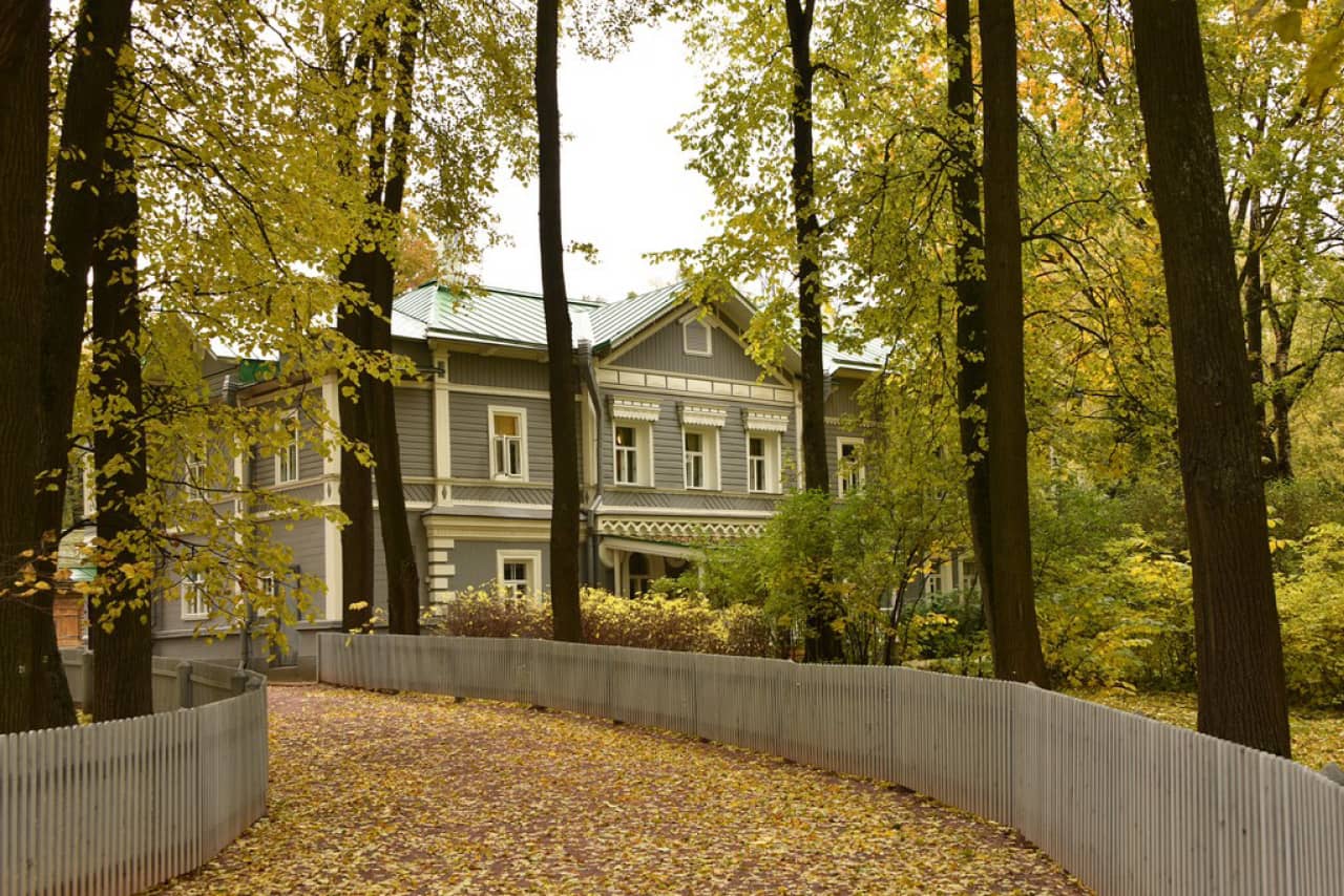 An old two-storey grey mansion in a park in autumn