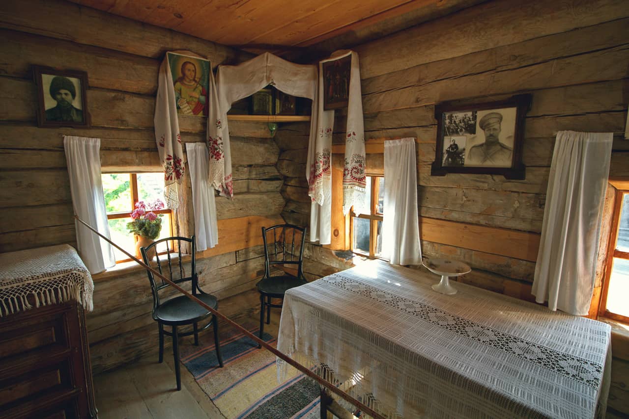 Interior of a Russian wooden house, pictures and an icon on a wooden wall, wooden table decorated with a white lace tablecloth