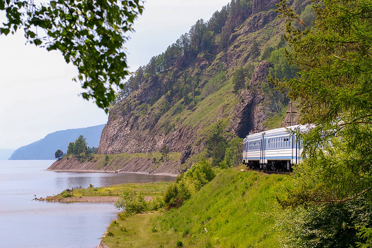 A Russian train moving on the railway track along the lake and beautiful landscape.