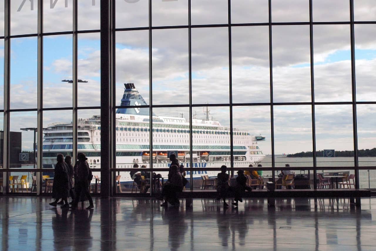 A sea port terminal with giant windows, a cruise ship behind the window