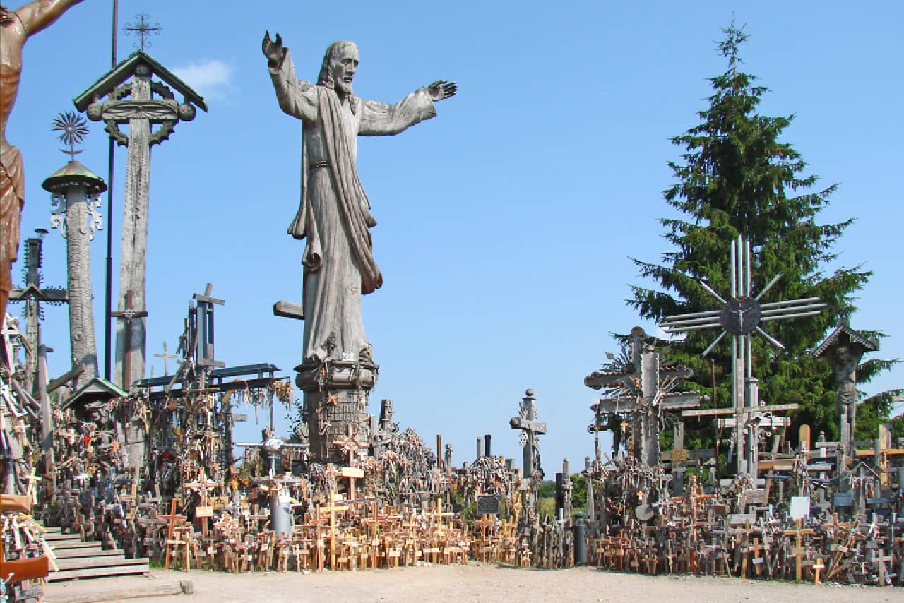 A wooden sculpture of Jesus surrounded with numerous wooden crosses