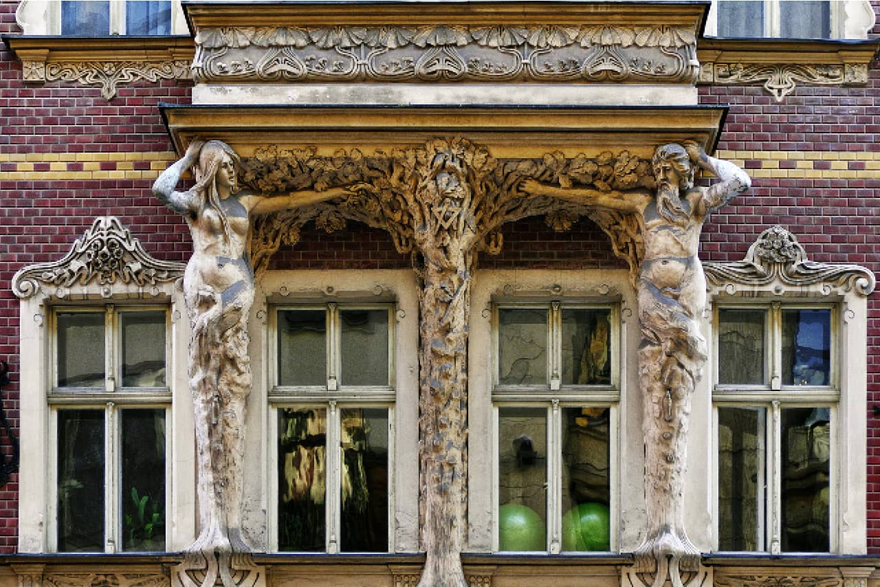 A beautiful decoration of windows with sculptures of a man and a woman on both sides trying to reach each other with a hand