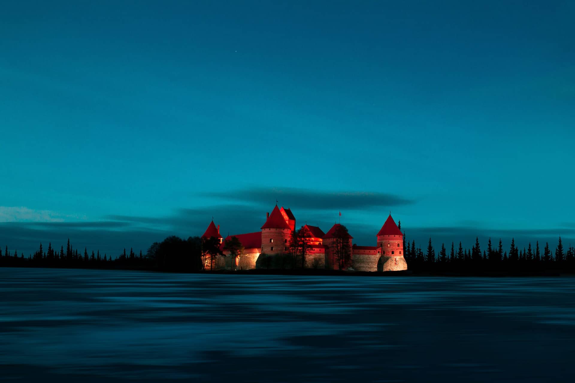 A red brick castle with round towers on an island