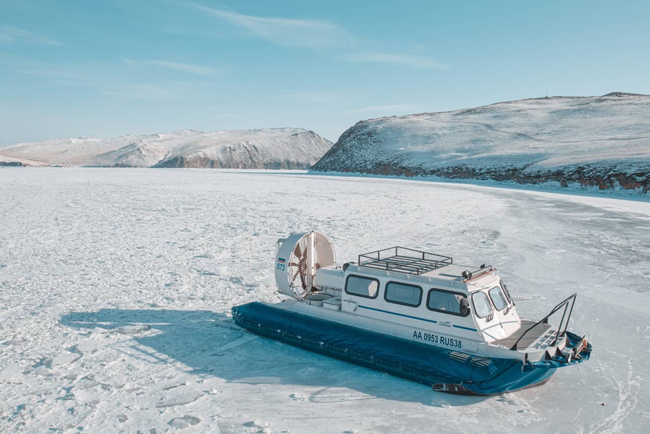 A Hovercraft on the ice of lake Baikal in winter, snowed up hills on the background