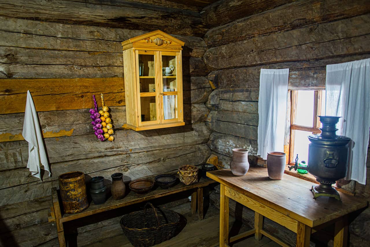 Interior of an old Russian wooden house, old wooden furniture and pottery for cooking, samovar