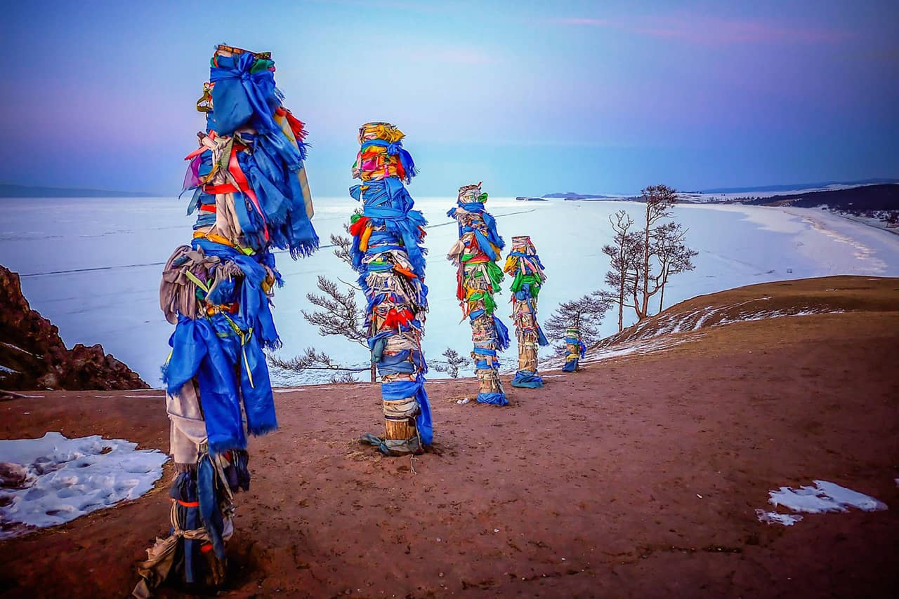 Several sacred piles decorated with colorful ribbons on a shore of a lake