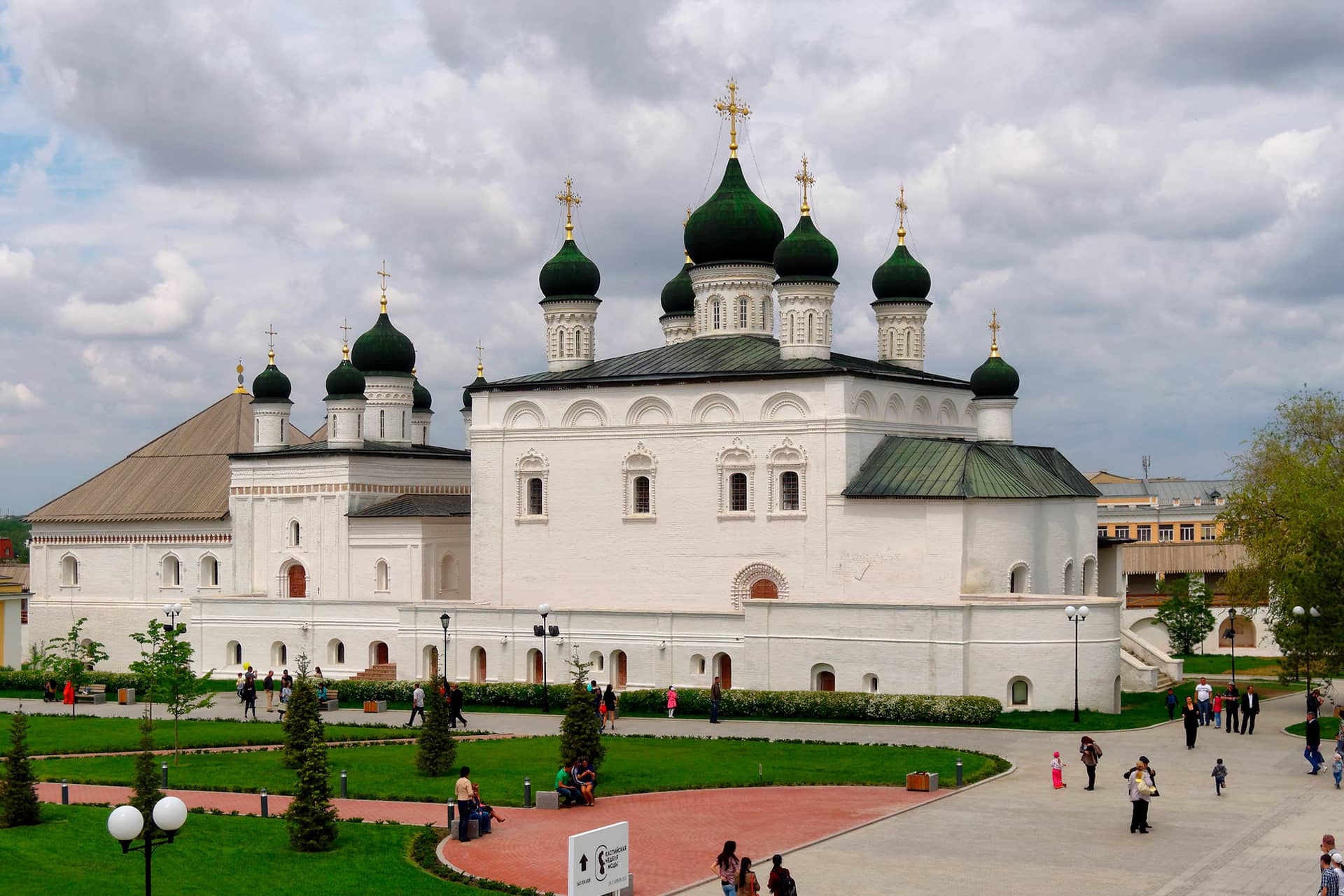 A white orthodox church consisting of two parts with many dark green domes