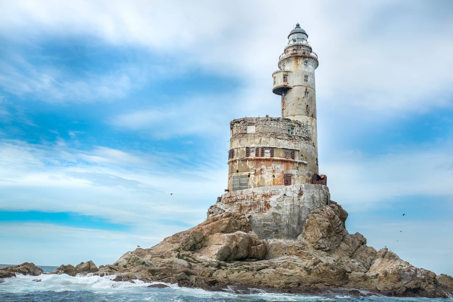 A picturesque lighthouse in the ocean on the top of a rock, ruined lighthouse