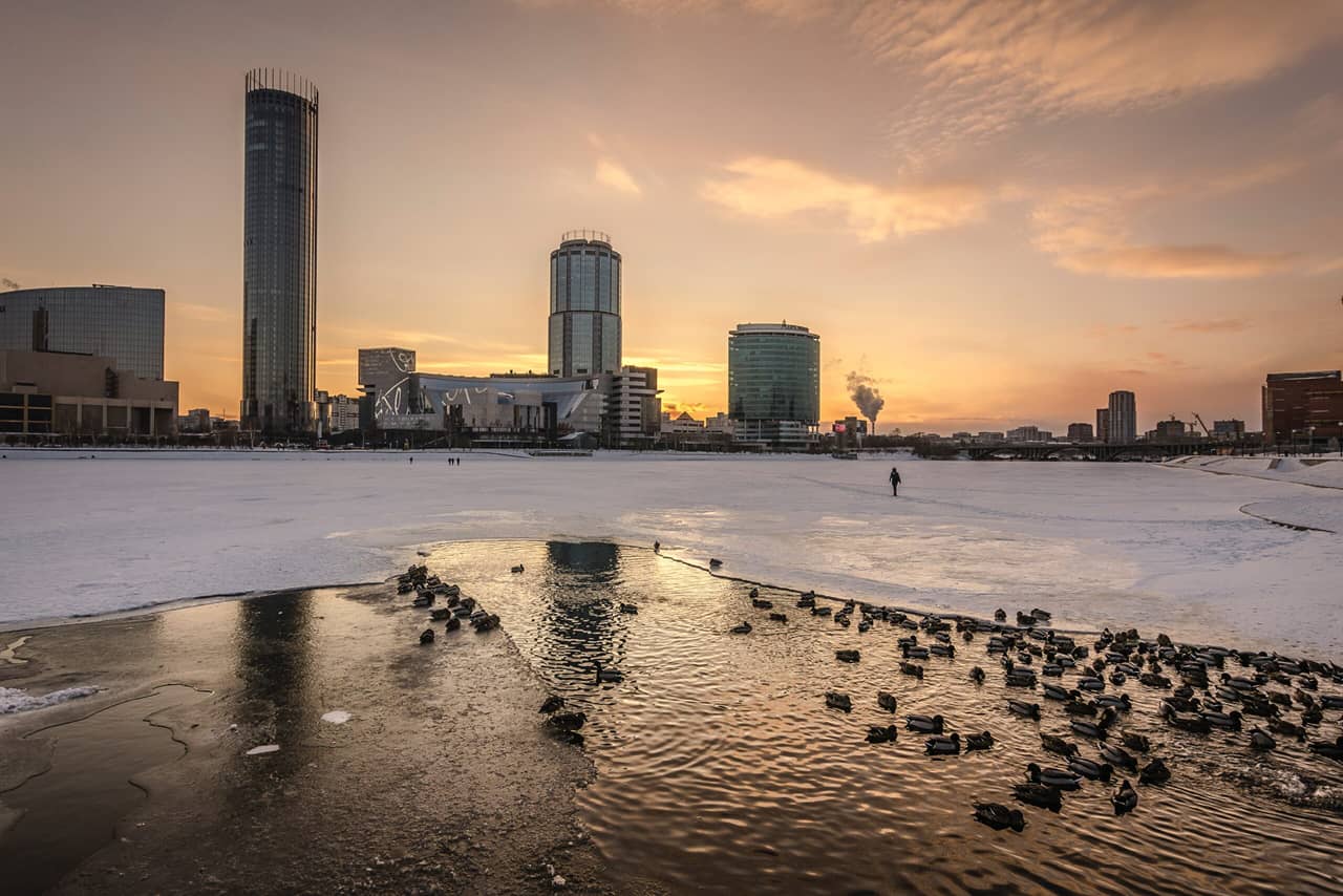 A frozen river and some skyscrapers in the distance