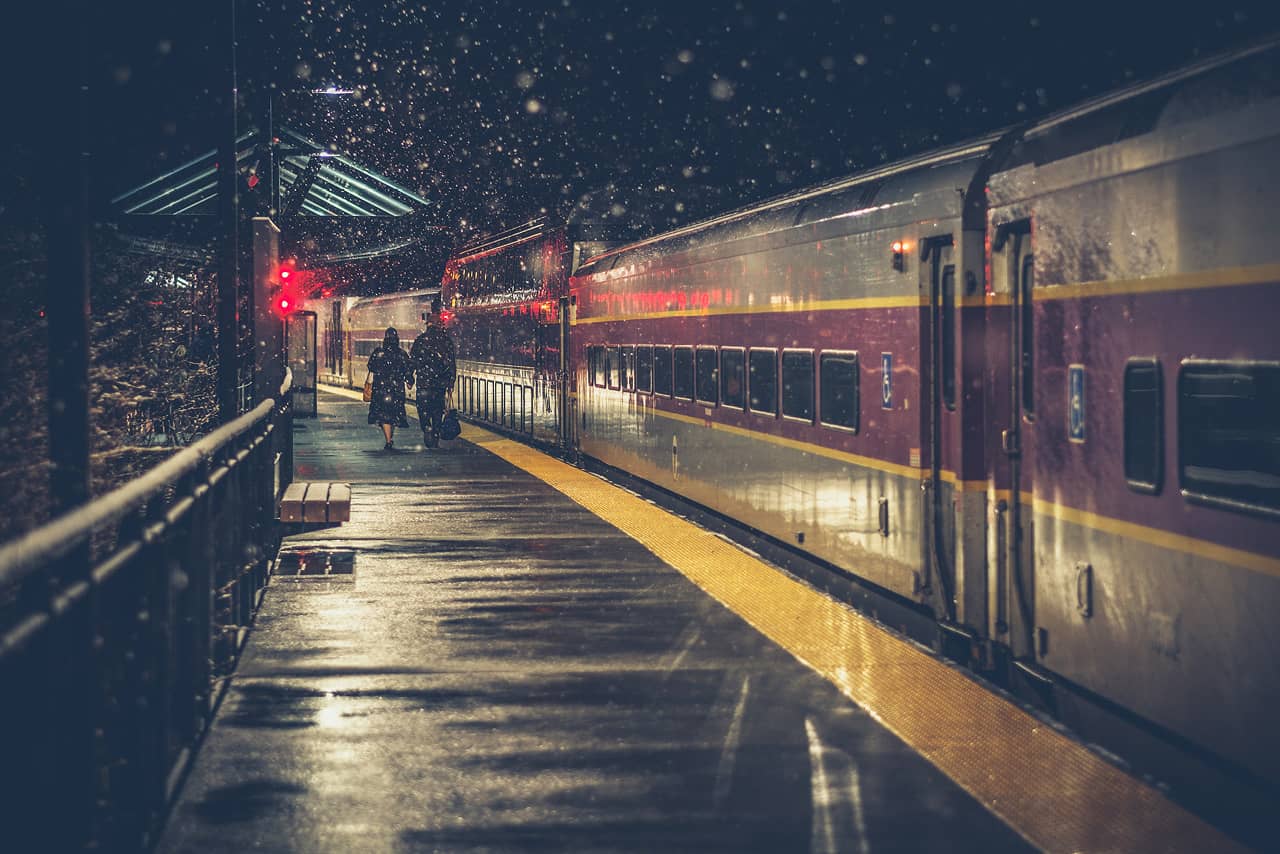A train at the station at night, snowy weather, two people at