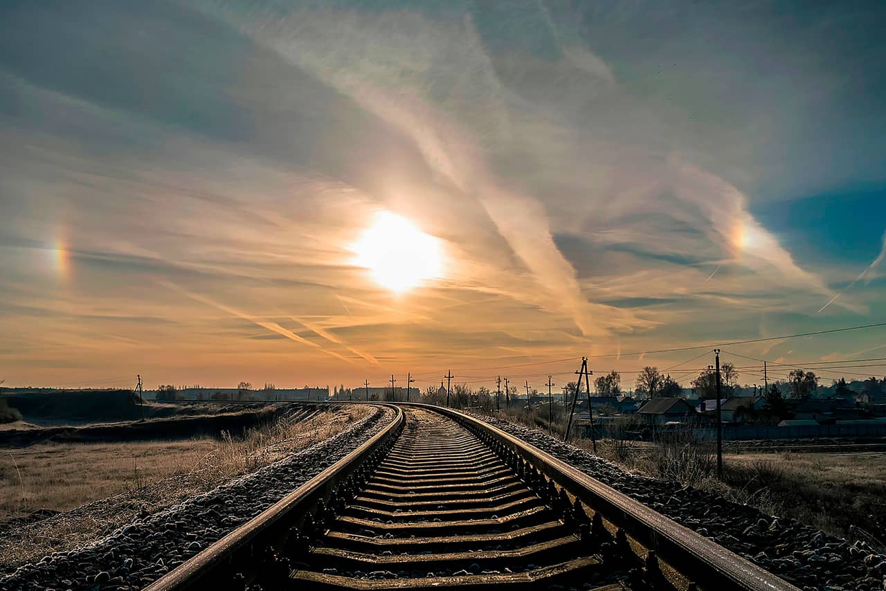 Train tracks crossing a village, beautiful sky with the sun