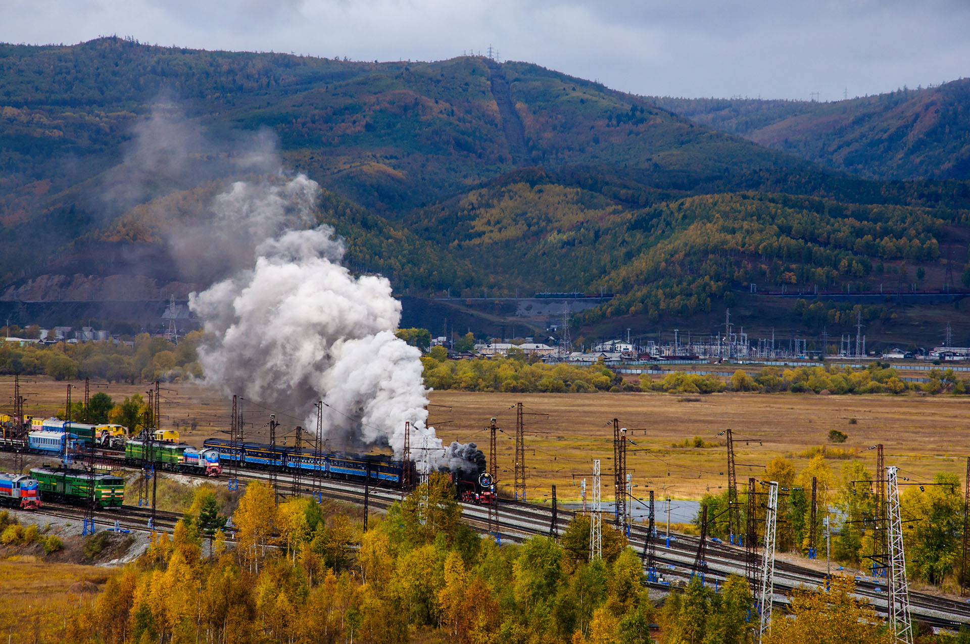 Old steam locomotive in the Circum-Baikal Railway with smoke in cloudy wearther autumn