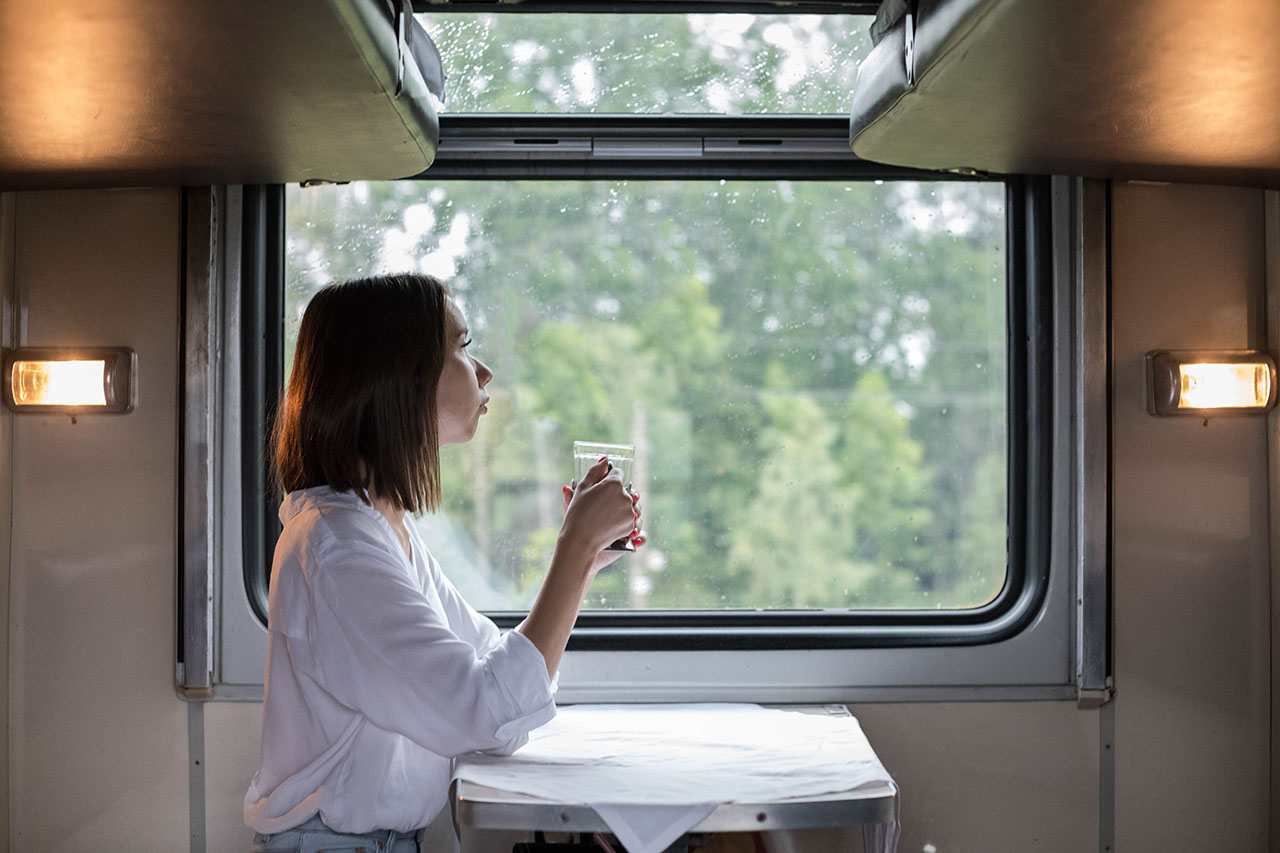 A young beautiful woman in a white shirt is sitting in a train c