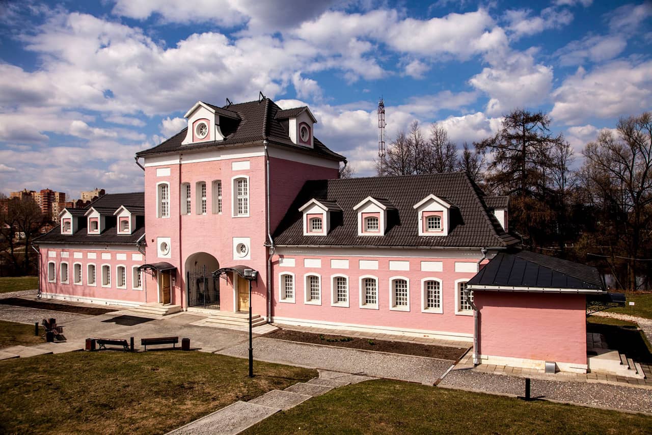 A pink and white mansion of two floors in the middle and one two symmetric parts of one floor on both sides